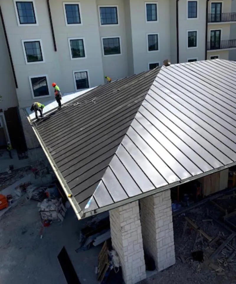 Crew installing standing seam metal roof panels on a commercial project in Bigfork